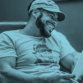 A photo of Watson sitting in a chair and smiling at something in front of him.